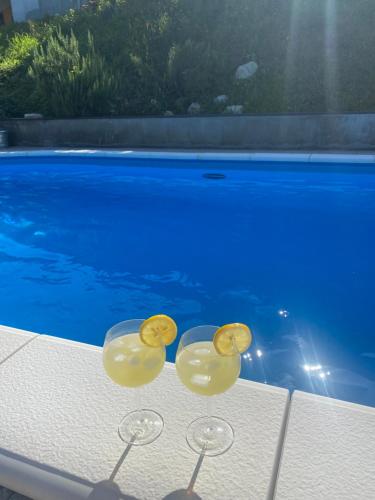 due bicchieri da vino seduti su un tavolo accanto alla piscina di Relax House Lara in Krapinske Toplice a Krapinske Toplice