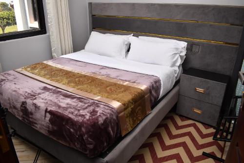 - une chambre avec un grand lit et une tête de lit dans l'établissement Cozy Apartment Entebbe, à Wakiso