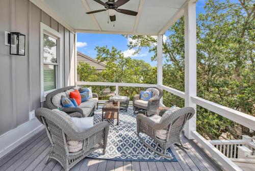 a screened in porch with wicker chairs and a table at Marsh Madness 5 Bdrm Low Country Lifestyle in Pawleys Island