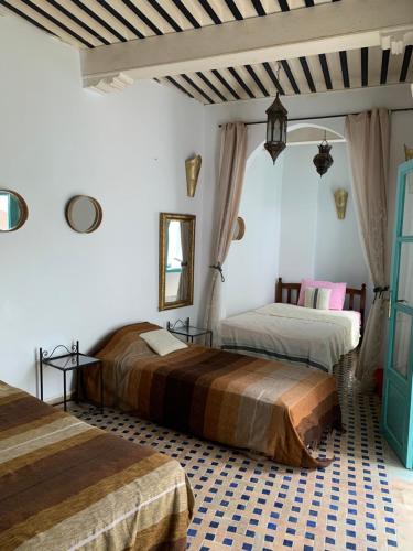 2 Betten in einem Zimmer mit weißen Wänden in der Unterkunft Riad Darko in Essaouira