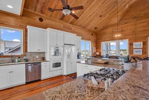 a large kitchen with white cabinets and a ceiling fan at Marsh Madness 5 Bdrm Low Country Lifestyle in Pawleys Island