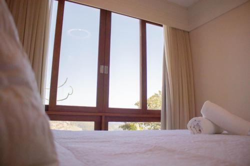a bedroom with a bed and a large window at Flat 333 - Luxo e Vista da Pedra Azul in Pedra Azul