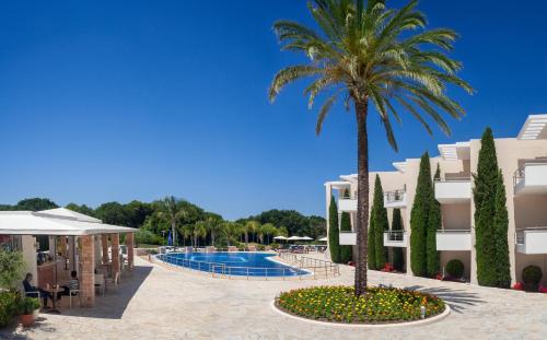 a resort with a palm tree and a swimming pool at Ionian Theoxenia in Kanali