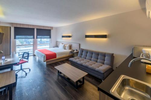 Habitación de hotel con cama y sofá en City Express Plus by Marriott Bogota Aeropuerto en Bogotá