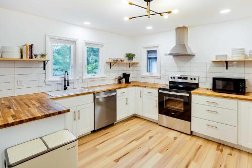 a large kitchen with white cabinets and wooden floors at Fully Remodeled Saugerties Retreat on 7 Acres! in Saugerties