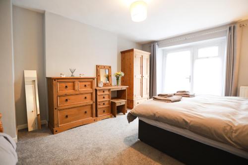 a bedroom with a bed and a dresser and a window at Woodside Oak hot tub & pool sleeps 4-6 in Bideford