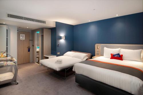 um quarto com 2 camas e uma parede azul em Holiday Inn Express - London Heathrow T4, an IHG Hotel em Hillingdon