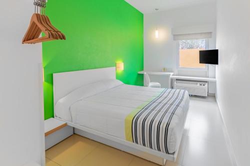 Dormitorio verde con cama blanca y pared verde en City Express Junior by Marriott Veracruz Aeropuerto, en Veracruz