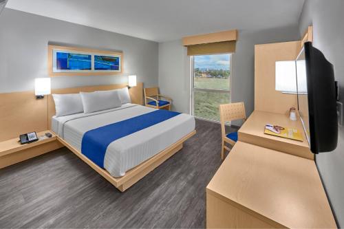 a bedroom with a bed and a desk with a television at City Express by Marriott Aguascalientes Sur in Aguascalientes
