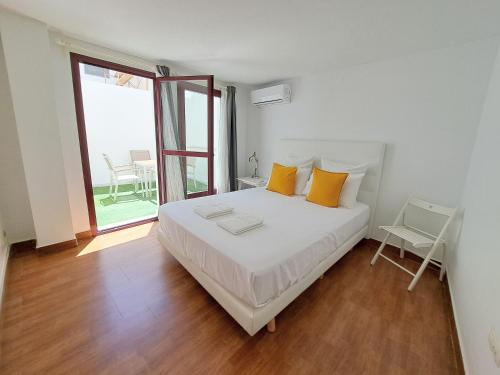 1 dormitorio con 1 cama blanca grande con almohadas amarillas en Apartamentos Sherry Center, en Jerez de la Frontera