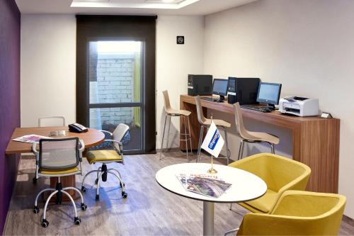 an office with tables and chairs and a desk with a computer at City Express by Marriott Leon in León
