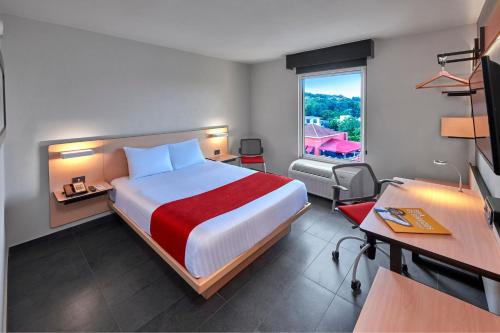 um quarto de hotel com uma cama, uma secretária e uma janela em City Express by Marriott Tampico em Tampico