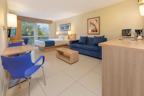 a hotel room with a bed and a blue couch at City Express by Marriott San José Costa Rica in San José