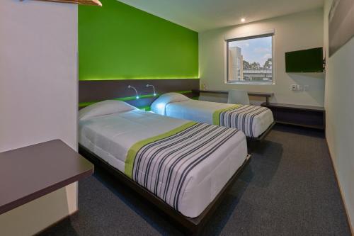 Cette chambre comprend 2 lits et un mur vert. dans l'établissement City Express Junior by Marriott Puebla FINSA, à Puebla