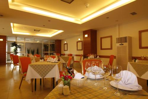a restaurant with tables and chairs with white tables and chairsktop at Muong Thanh Holiday Da Lat Hotel in Da Lat