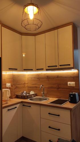 a kitchen with white cabinets and a sink and a light at Apartman Green in Šišava