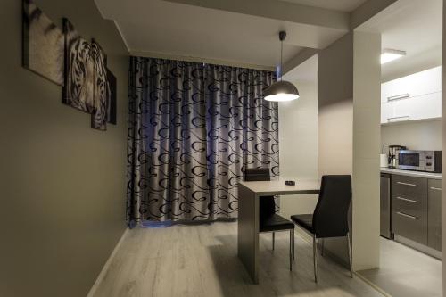 cocina con mesa, sillas y cortina en Apartament Perla Falezei, en Galaţi