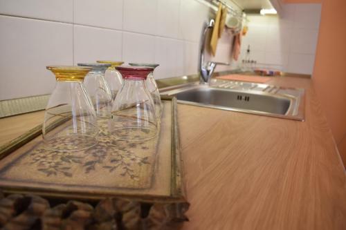 three glass bottles sitting on a counter next to a sink at ΆLthea Apartment in Chalkida