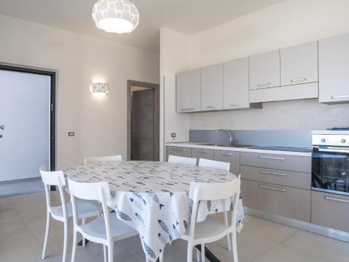a kitchen with a table and white cabinets and white chairs at Villa Marisa - Villa di Lusso Fronte Spiaggia in Cittadella del Capo