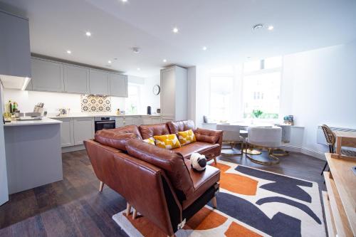 a living room with a brown leather couch and a kitchen at Sophia's Cwtch in Cardiff