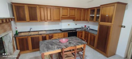 una cucina con armadi in legno e un tavolo con ciotola di Casa Rosina a Castrignano del Capo
