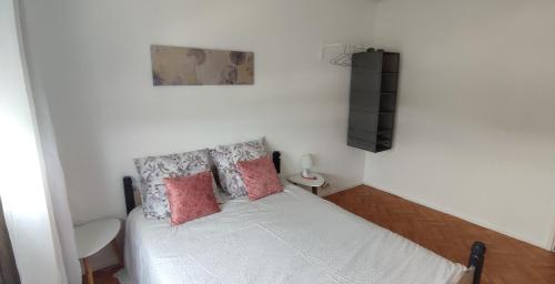una piccola camera da letto con un letto bianco con cuscini rosa di Appartement entier paisible proche Tours a Joué-lés-Tours