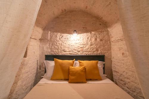 阿爾貝羅貝洛的住宿－Trullo Arboris，石头间内的一张床位,配有黄色枕头
