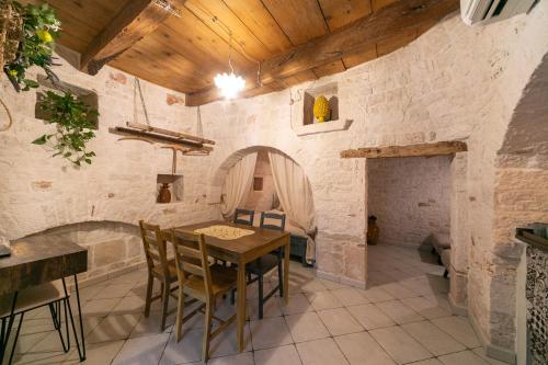a dining room with a table and a stone wall at Trullo Arboris in Alberobello