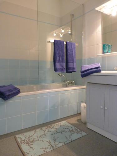 W łazience znajduje się wanna, umywalka i fioletowe ręczniki. w obiekcie La Désirade w mieście Salles-la-Source