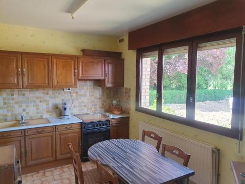 een keuken met houten kasten en een tafel en een raam bij Beatitude62 in Fauquembergues