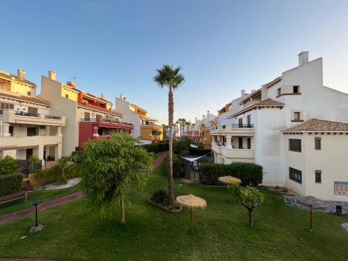 une cour avec un palmier et quelques bâtiments dans l'établissement Lila, à Ayamonte