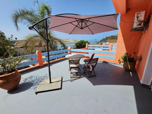 a patio with a table and chairs and an umbrella at Lagon appartement in Moulay Bousselham
