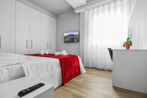 um quarto branco com uma cama com um cobertor vermelho em Appartamento VITTORIA em Verona