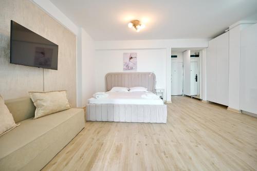 a white bedroom with a bed and a couch at TGM Sunrise View in Infinity Pool & Spa Resort in Mamaia Sat/Năvodari