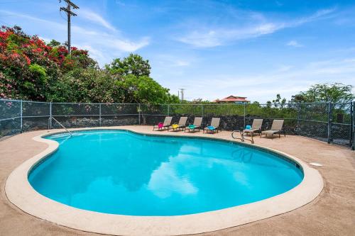 a swimming pool with chairs and a fence at Kona Mansions#105 in Kailua-Kona