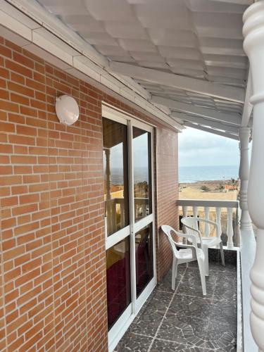 a patio with two white chairs and a brick wall at Casa BB&Djassi in Ponta do Sol