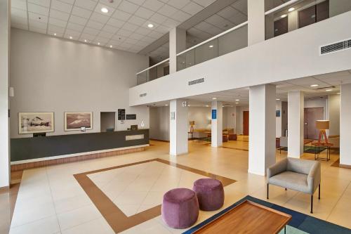 a lobby of a hospital with a chair and stool at City Express by Marriott Puebla Angelopolis in Puebla