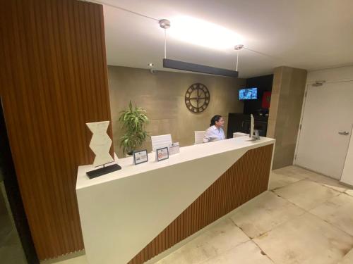 a woman sitting at a counter in a lobby at Grau Business Hotel in Piura