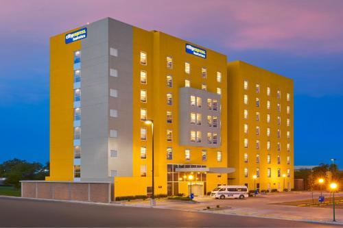 a yellow building with a van parked in front of it at City Express by Marriott Monterrey Lindavista in Monterrey