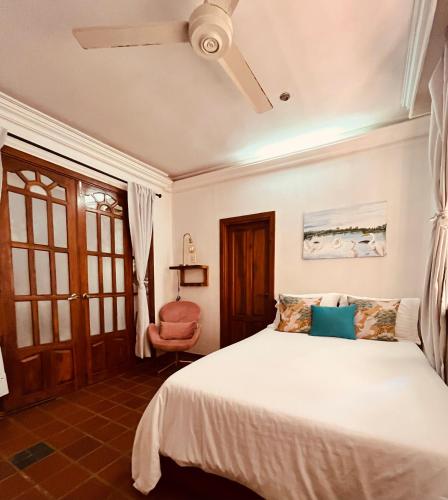 a bedroom with a white bed and a chair at Casa Isabelita in Mompos