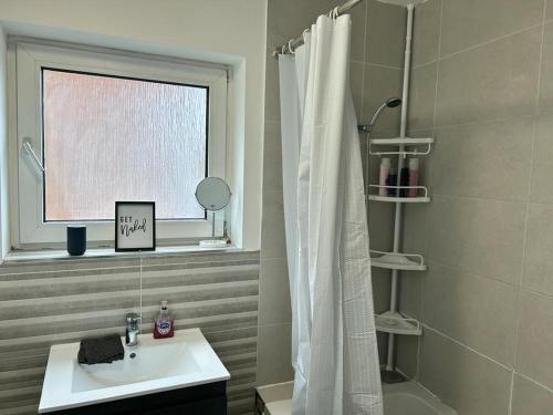 a bathroom with a sink and a shower curtain at 4 Bedroom Flat In Watford in Leavesden Green