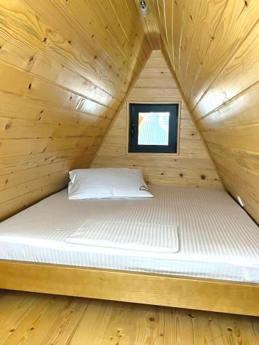 a bed in a wooden cabin with a window at WoodSide Žabljak in Žabljak