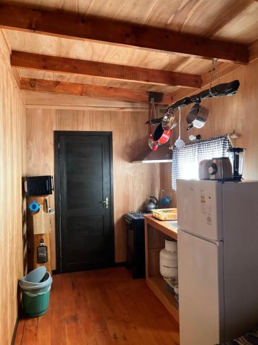 uma cozinha com uma porta preta e um frigorífico em El banzai em Punta Del Diablo