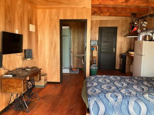 a bedroom with a bed and a desk and a refrigerator at El banzai in Punta Del Diablo