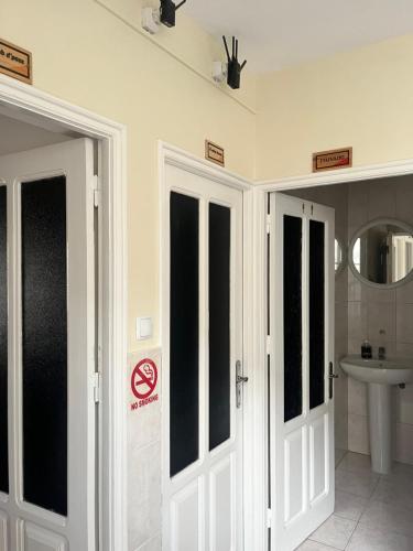 een badkamer met twee witte deuren en een wastafel bij Casa BB&Djassi in Ponta do Sol