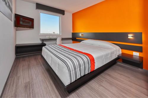a bedroom with a bed with an orange wall at City Express Junior by Marriott San Luis Potosi Carranza in San Luis Potosí