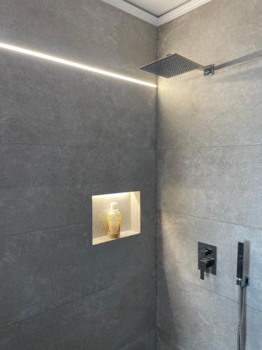 a bathroom with a shower with a yellow vase on the wall at Aquamarine Dreams Apartments in Beach of Durres 150 m from Sea in Durrës