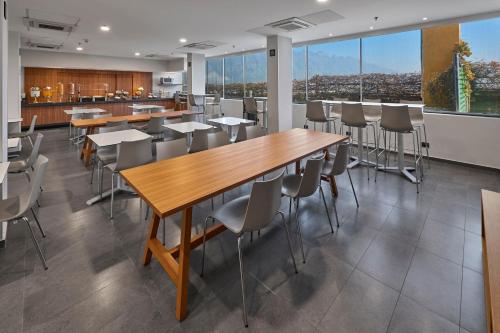 Un comedor con mesas y sillas y grandes ventanales. en City Express by Marriott Monterrey Santa Catarina, en Monterrey