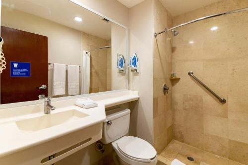 a bathroom with a toilet and a sink and a shower at City Express by Marriott Cancun in Cancún