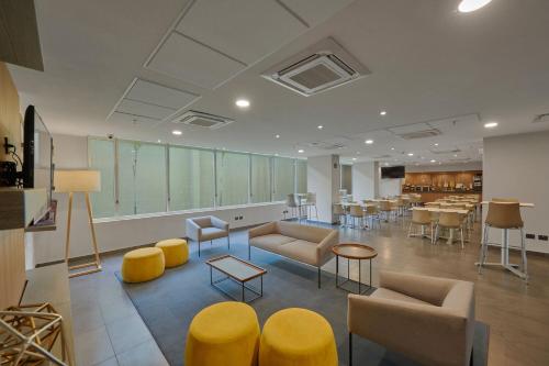 a lobby with couches and tables and yellow chairs at City Express by Marriott Tampico Altamira in Tampico
